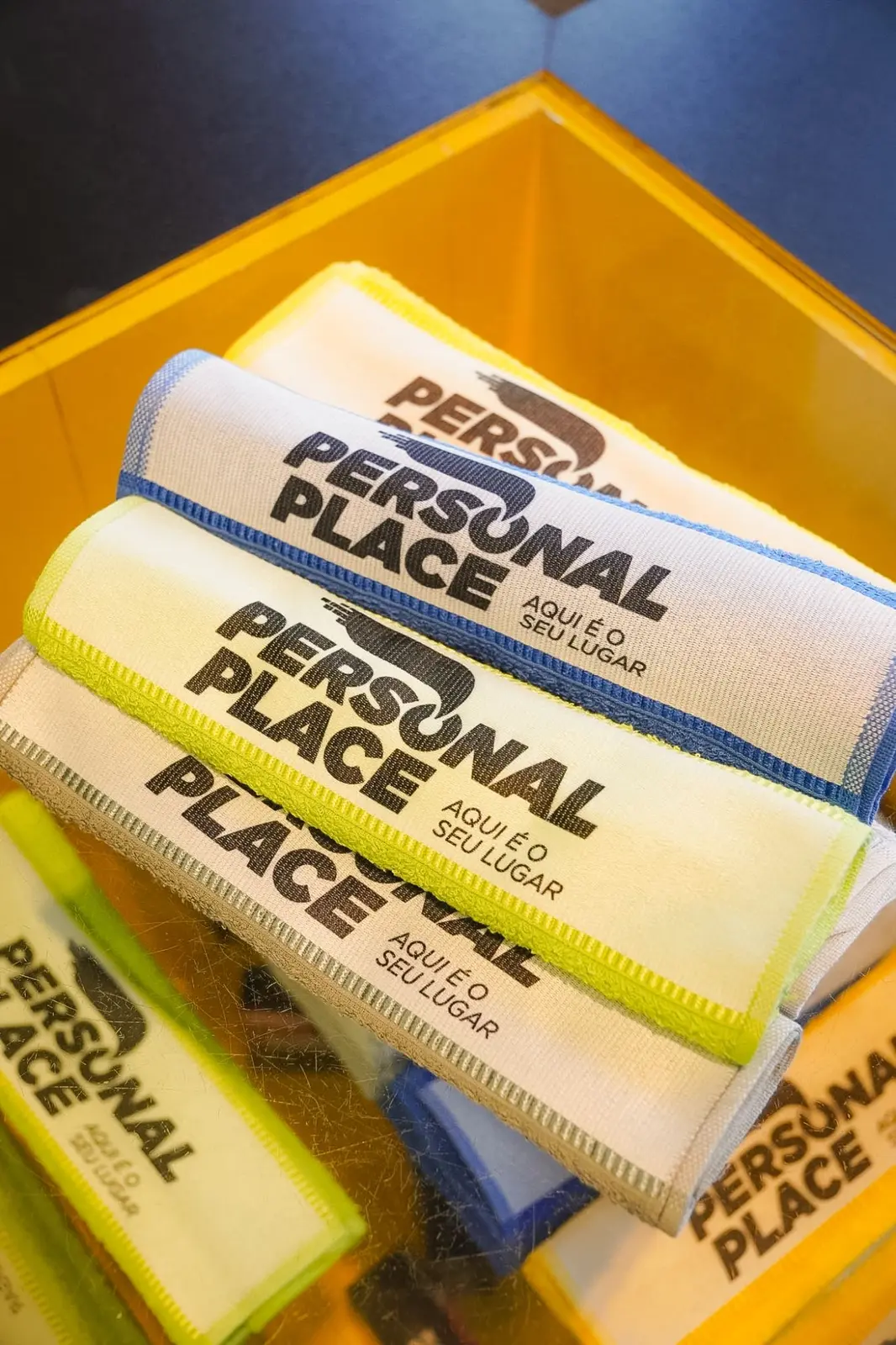 Toalhas de treino Personal Place empilhadas, com faixa branca estampada e bordas coloridas